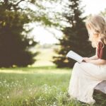 woman sitting while reading book