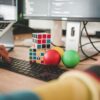 person using computer and two Rubik's Cube near monitor