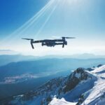 white quadcopter drone flying near snow mountain during daytime