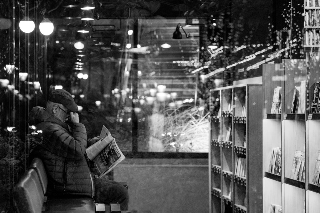 grayscale photo of woman in black jacket sitting on chair